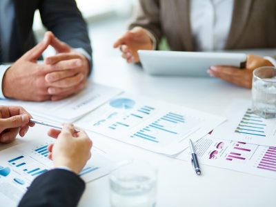 Image of business documents, pen and glasses on workplace during meeting of partners